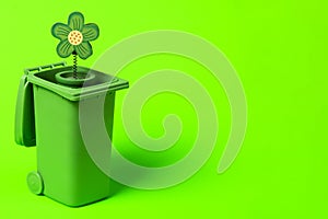 Green trash can with flowers on a green background