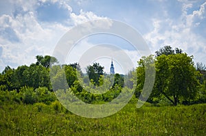 Green trees and a church in the distance.