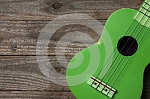 Green ukulele on a wooden table, copy space