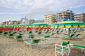 Green umbrellas and chaise lounges on the beach of Rimini in Italy