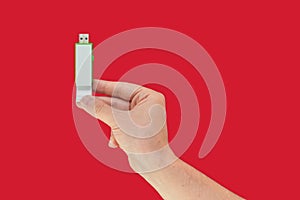 Green USB flash on hand with isolated red background