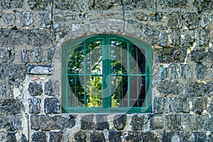 Green vaulted window on a cinder block wall