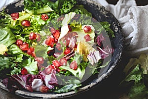 Green vegan salad in bowl with endive, arugula, mixed lettuces and pomegranate