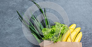 Green vegetables in shopping bag on light stone background