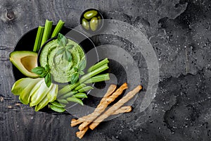 Green vegetables snack board with herb hummus or pesto dip. Healthy raw summer appetizer platter.