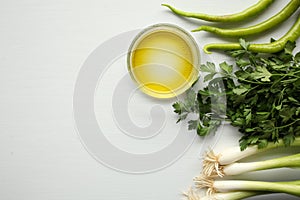 Green vegetables on white background: paprika, parsley, olive oil, onion