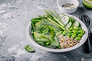 Green vegetarian buddha bowl salad with fresh vegetables and quinoa, spinach, avocado, asparagus, cucumber, edamame beans