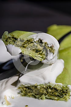 Green vegetarian spring rolls, spinach pancake with sour cream on a white plate, closeup. Healthy breakfast concept