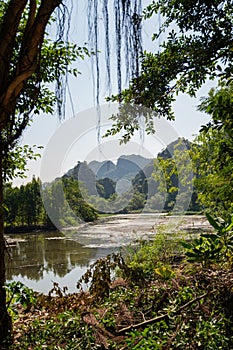 Green Vegitation with Lake in Foreground and green mountains in the background with blue skies in Vietnam photo