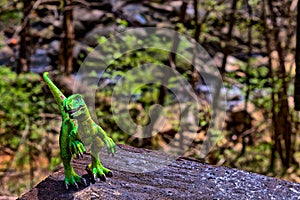 Green Velociraptor dinosaur with woods in the background
