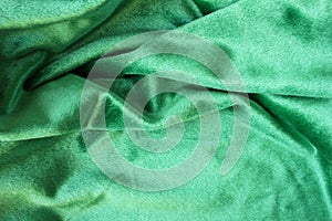 Green velour fabric texture. Wavy folds background. Fragment of a drapery dark green cloth material