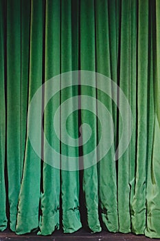 Green velvet curtains pooling on stage