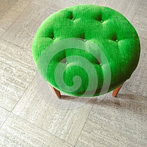 Green velvet stool on tiled floor