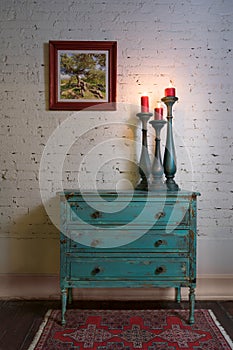 Green vintage cabinet, candlesticks and hanged painting on bricks wall