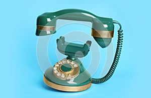 Green vintage corded phone on blue background