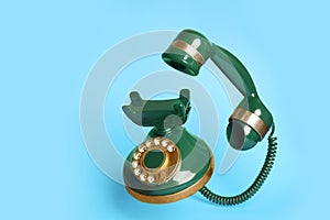 Green vintage corded phone on blue background