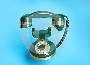 Green vintage corded phone on light blue background