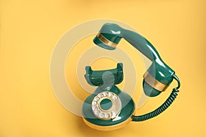 Green vintage corded phone on yellow background