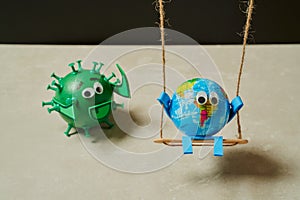 Green virus catching a toy earth on a swing