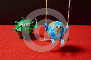 Green virus pushing a toy earth on a swing