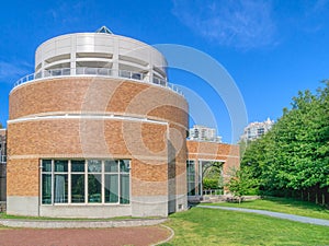 Green wall of trees and mowed lawn along the round shaped office building