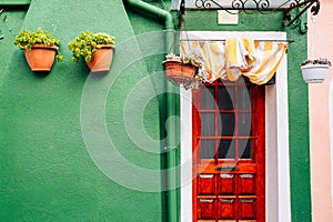 Green wall and wooden door in Burano island, Venice, Italy