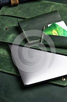 green wallet and genuine leather laptop case and cardholder lie on table