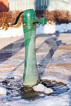 Green water pump on a sunny winter day