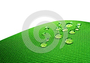 Green waterproof fabric with waterdrops close up on white