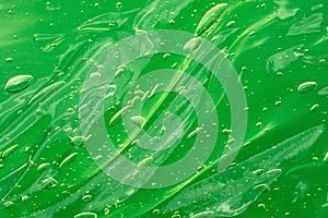 Green waved serum with bubbles on the green background.Cosmetics smear of aloe vera or antibacterial gel.Good as mockup with copy