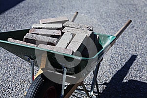 A green wheelbarrow filled with curbs from the front