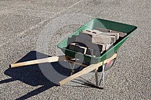 A green wheelbarrow filled with curbs