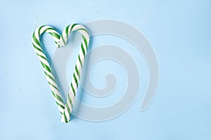 Green and white candy cane in the shape of heart on the blue background