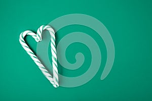 Green and white candy cane in the shape of heart on the green background