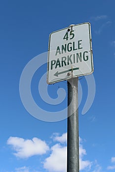 Green and white 45 degree Angle Parking sign in a blue sky