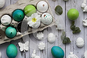 Green and white Easter eggs in egg carton. Candle egg, gypsum egg, poultry egg with ground and white blossom