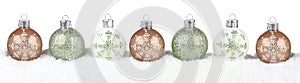 Green, white and gold Christmas ornaments in snow isolated