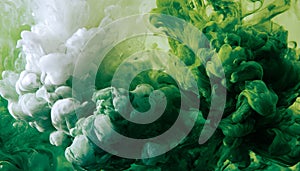 Green and white ink diffusing in water, forming swirling clouds.