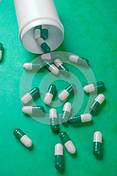 Green and white pills spilling from white bottle