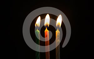 Green white pink birthday candle yellow lights burning in the dark and black background