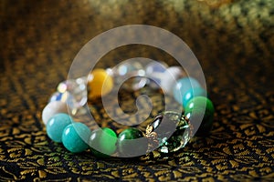 Green and white tone lucky stone bracelet. green moss agate, Green tiger`s eye, jade on Thai traditional golden tone fabric backgr