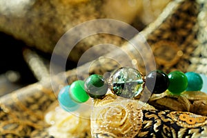 Green and white tone lucky stone bracelet. green moss agate, Green tiger`s eye, jade on Thai traditional golden tone fabric backgr