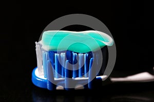 Green and white toothpaste on a blue and white toothbrush