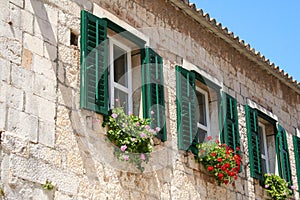 Green windows on the facade old stones house.