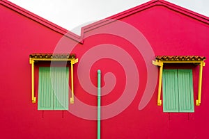 Green windows on a red wall house on the street