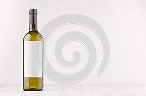 Green wine bottle with blank white label on white wooden board, mock up.