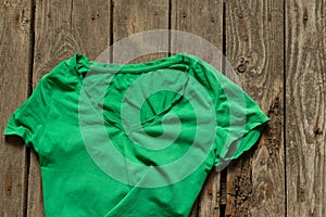 Green women`s t-shirt lies on a wooden background close up