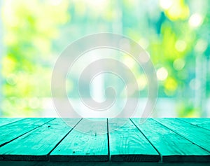 Green wood table top on blur abstract green garden from window view