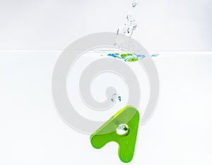 Green wooden alphabet A drop in the water with white background and selective focus
