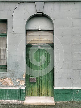 A green wooden door with a lunette above